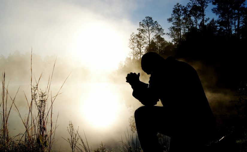 Man praying at sunset
